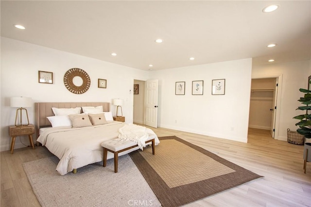 bedroom with a walk in closet and light hardwood / wood-style flooring