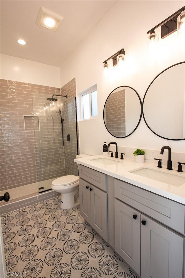 bathroom with a tile shower, tile patterned flooring, vanity, and toilet