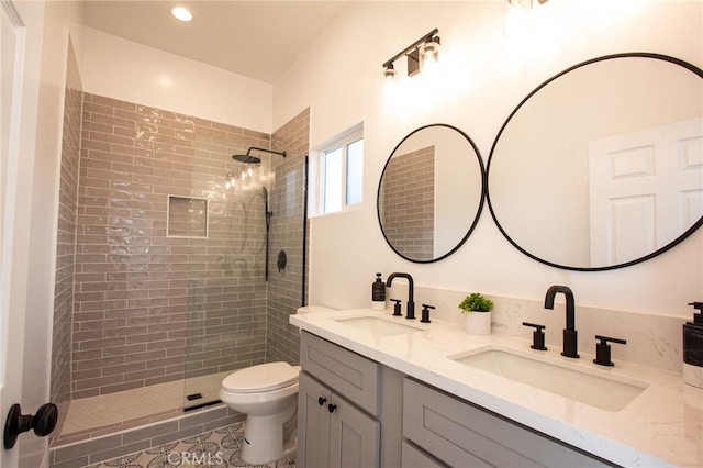 bathroom featuring tiled shower, vanity, tile patterned floors, and toilet