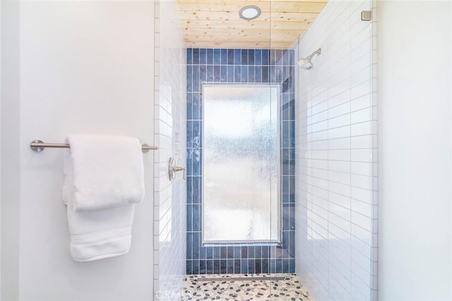 bathroom featuring a tile shower and wood ceiling