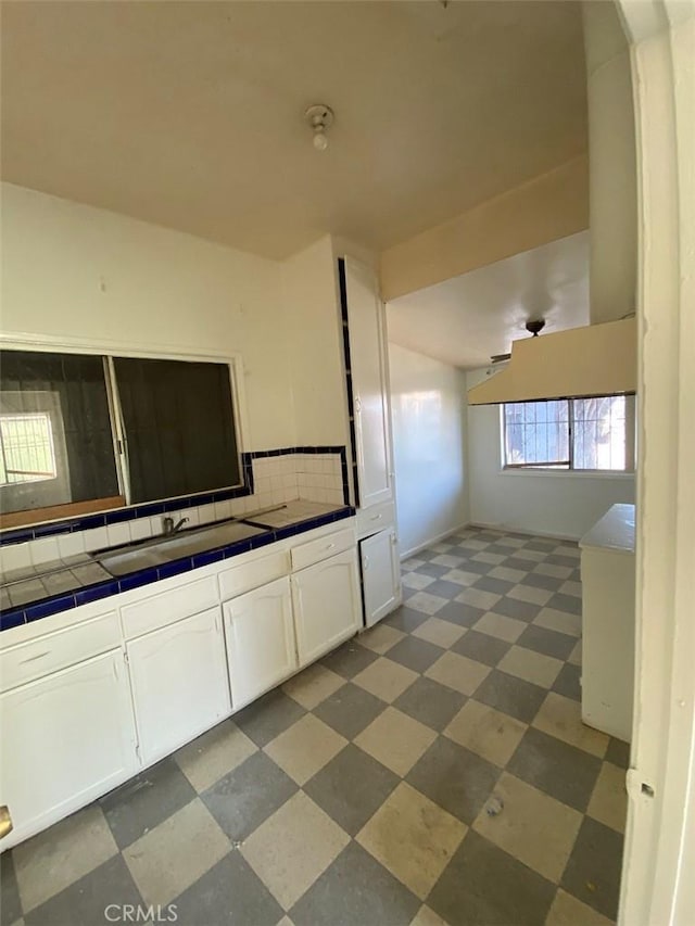 kitchen with tile counters, white cabinetry, and tasteful backsplash