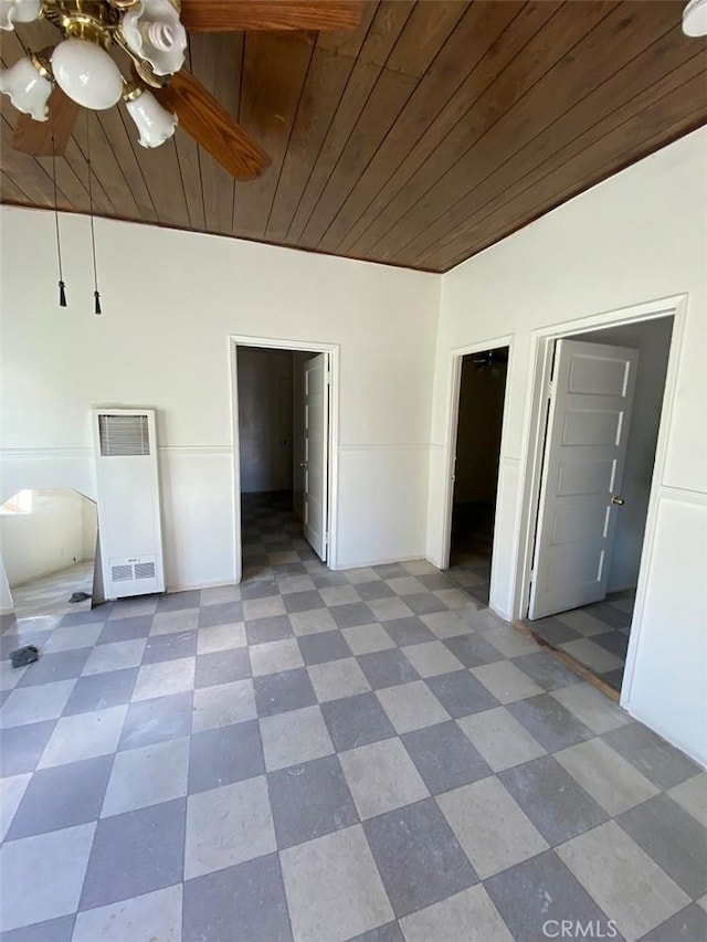 unfurnished bedroom with a spacious closet, ceiling fan, wood ceiling, and connected bathroom