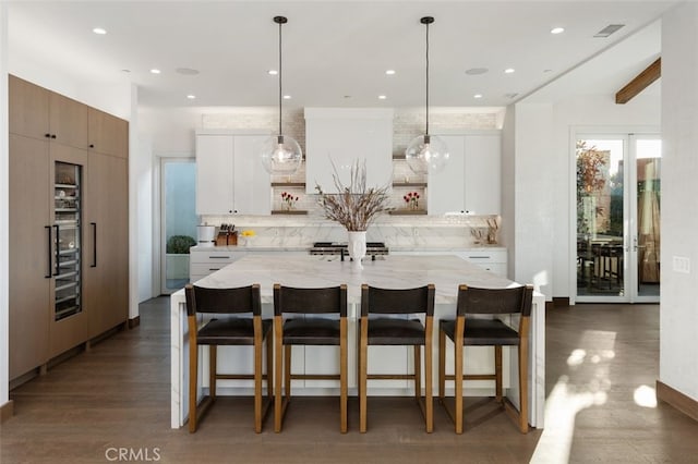 kitchen with white cabinets, backsplash, and an island with sink