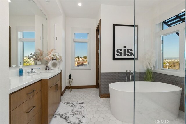 bathroom with tile patterned flooring, vanity, a bath, and tile walls