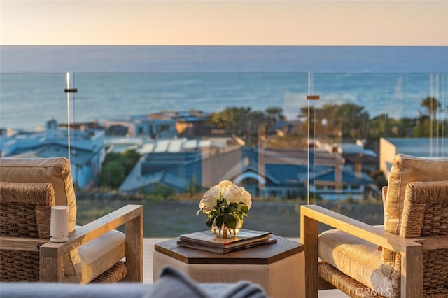 balcony at dusk featuring a water view