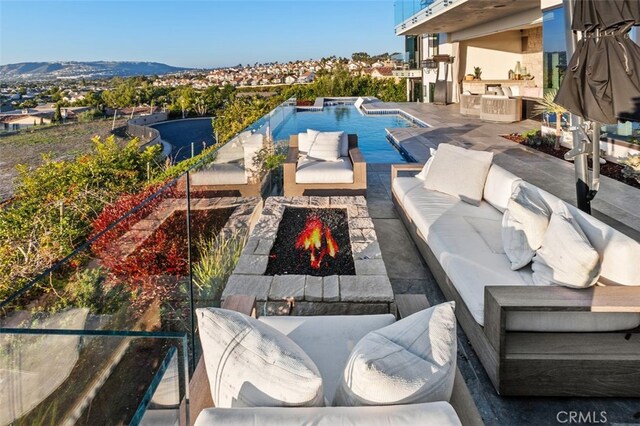 view of swimming pool with a mountain view, an outdoor living space with a fire pit, and a patio area