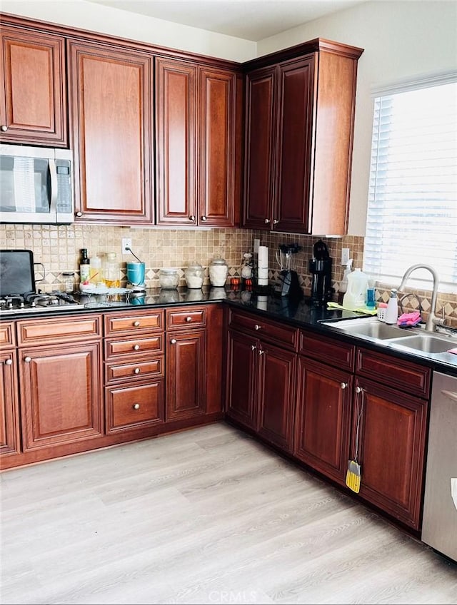 kitchen featuring tasteful backsplash, sink, stainless steel appliances, and light wood-type flooring