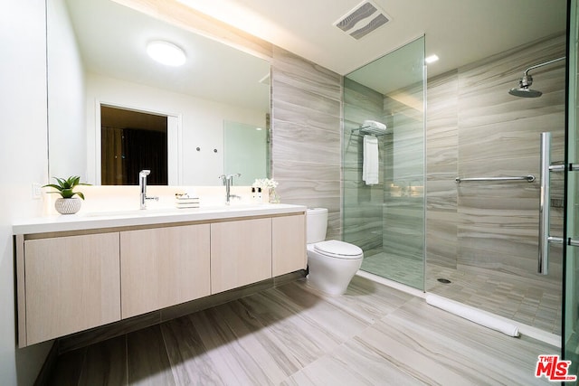 bathroom with dual vanity, toilet, tile patterned flooring, and a shower with shower door