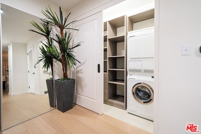 laundry room featuring light wood-type flooring and stacked washer / drying machine