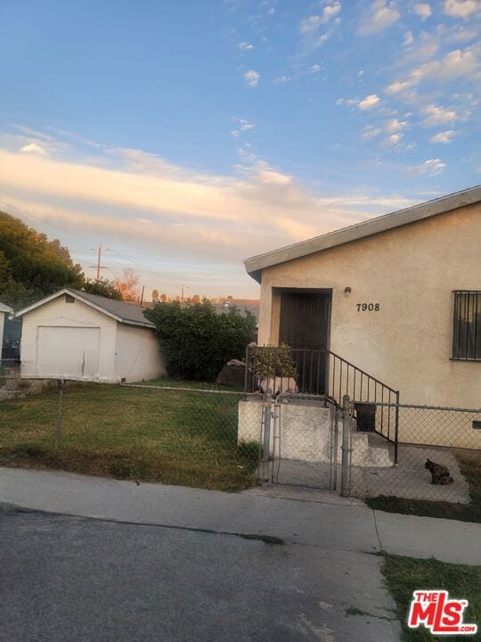 property exterior at dusk with a yard and an outbuilding