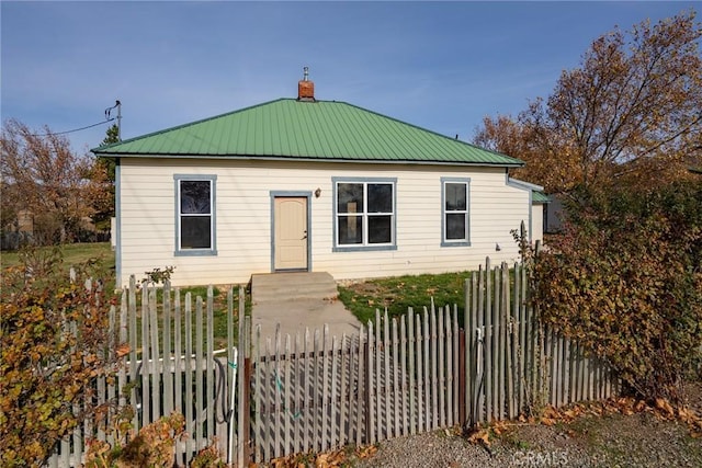 view of front of house featuring metal roof, a chimney, and a fenced front yard