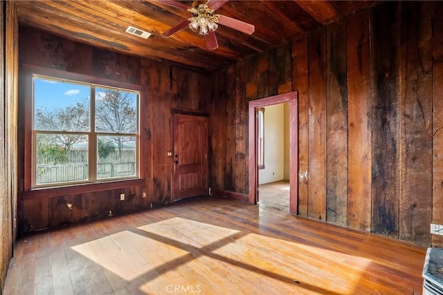 spare room with wooden ceiling, visible vents, wooden walls, and wood finished floors