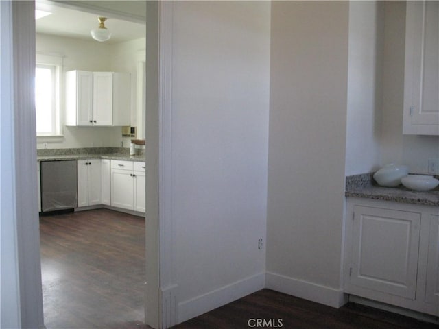 kitchen with stainless steel dishwasher, light stone counters, white cabinetry, and dark wood-type flooring