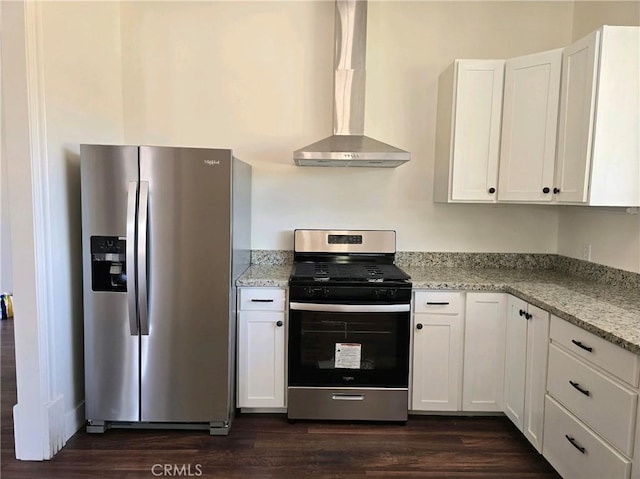 kitchen with light stone countertops, appliances with stainless steel finishes, wall chimney exhaust hood, white cabinets, and dark hardwood / wood-style floors