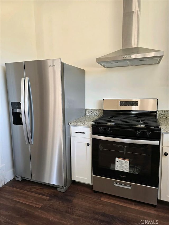 kitchen with dark hardwood / wood-style flooring, white cabinets, stainless steel appliances, and wall chimney range hood