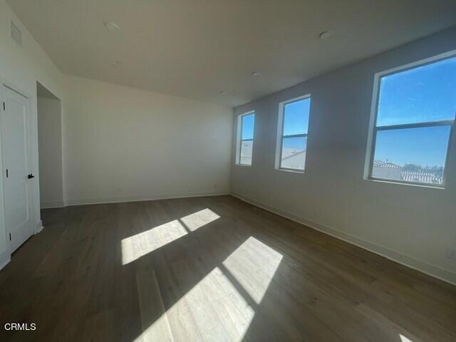 unfurnished room with wood finished floors, baseboards, and a wealth of natural light