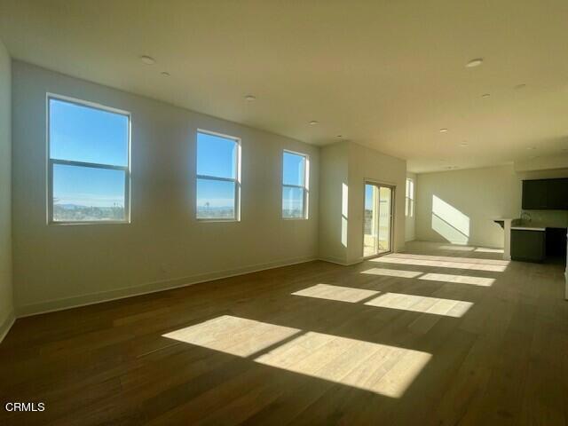 unfurnished living room with wood finished floors and baseboards