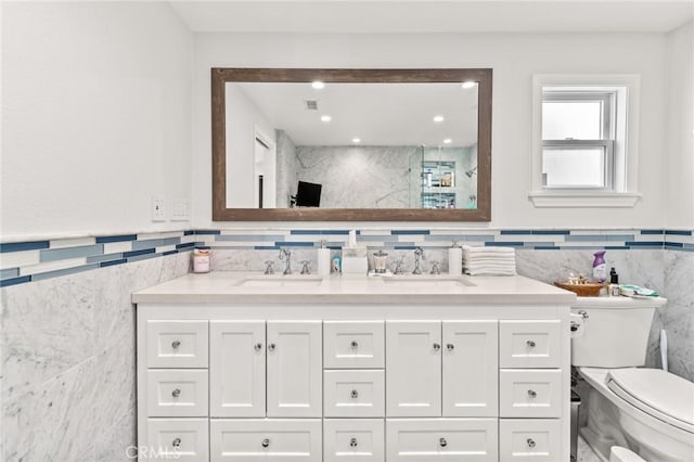 bathroom with vanity, toilet, and tile walls