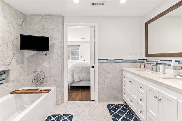 bathroom featuring vanity, a bathtub, and tile walls