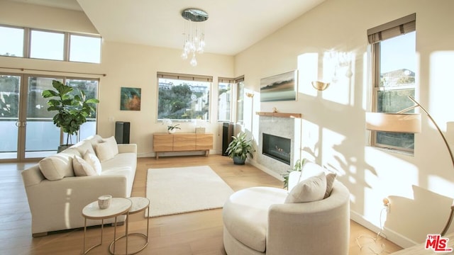 living room featuring light wood-type flooring, a fireplace, and an inviting chandelier