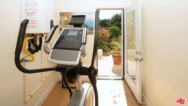 workout room with light hardwood / wood-style floors and water heater