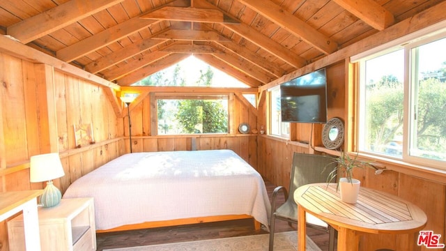 bedroom featuring multiple windows, wooden walls, lofted ceiling with beams, and hardwood / wood-style flooring