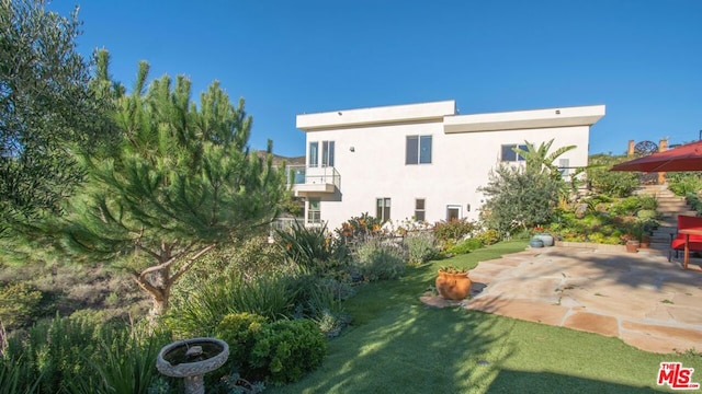 rear view of house with a yard, a patio area, and a balcony