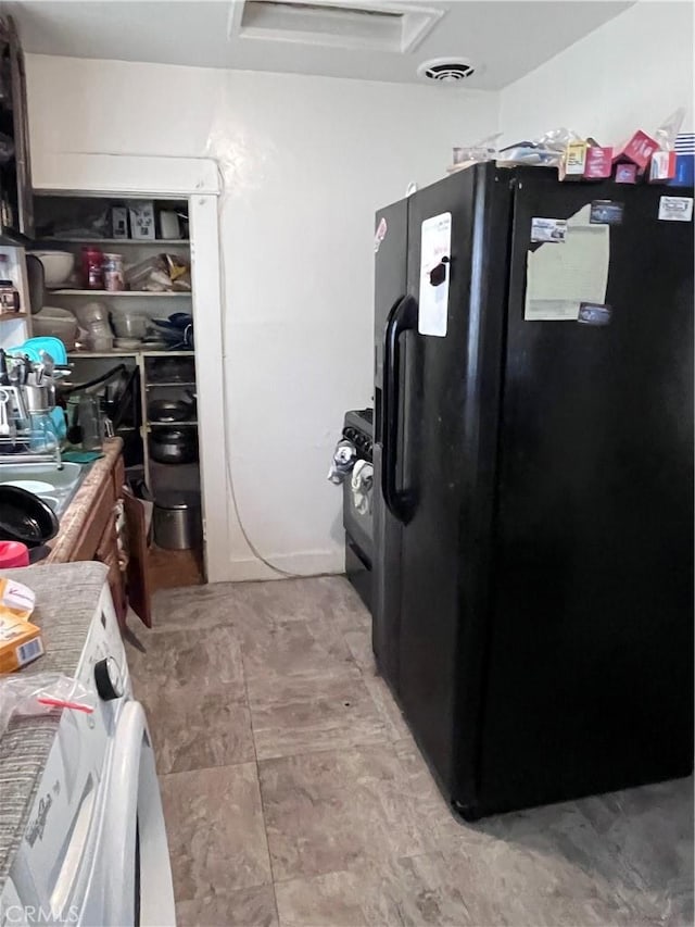 kitchen featuring light tile floors and black refrigerator