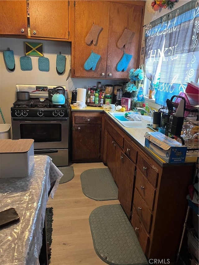 kitchen featuring sink, gas stove, and light wood-type flooring