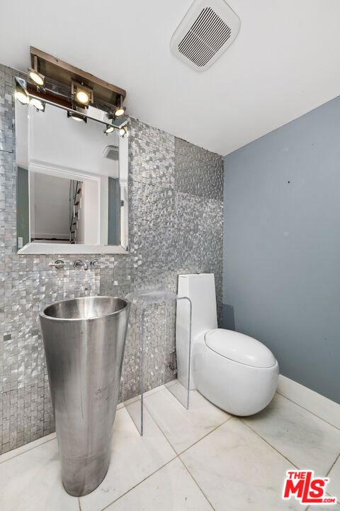 bathroom with toilet, tasteful backsplash, and tile walls