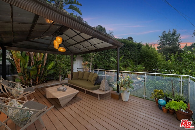 deck at dusk featuring outdoor lounge area and ceiling fan