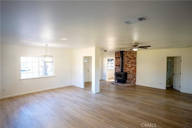 unfurnished living room with hardwood / wood-style flooring, a wood stove, and ceiling fan