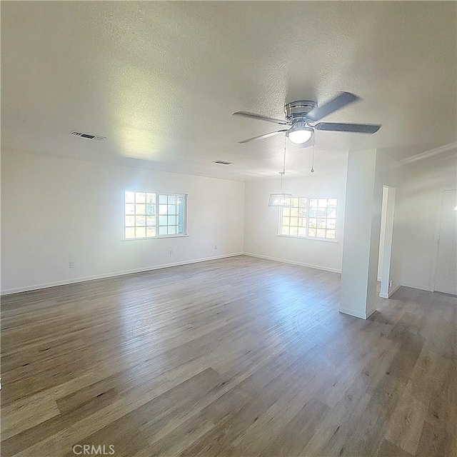 spare room with ceiling fan, a healthy amount of sunlight, a textured ceiling, and wood-type flooring