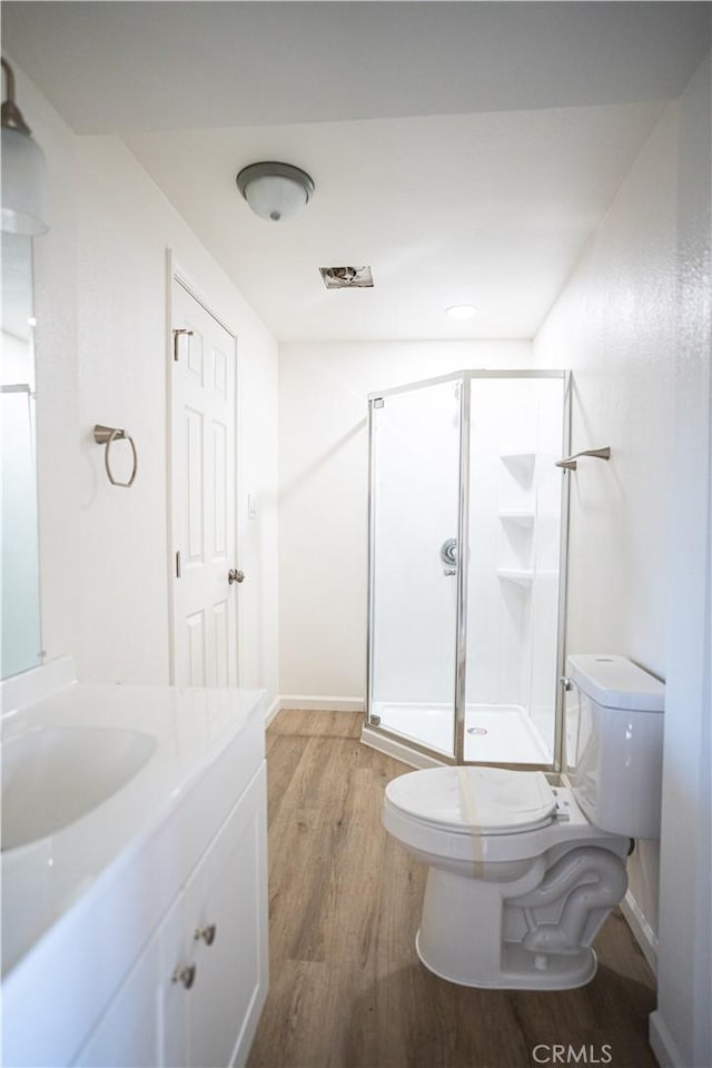 bathroom featuring hardwood / wood-style floors, vanity, toilet, and a shower with shower door