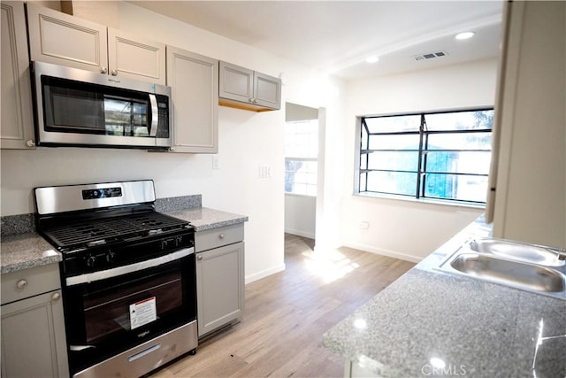 kitchen featuring light stone countertops, sink, stainless steel appliances, light hardwood / wood-style flooring, and gray cabinets