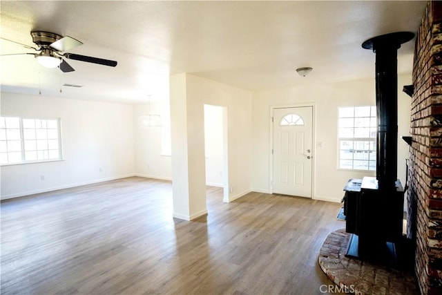 entryway featuring hardwood / wood-style floors, ceiling fan, and a wood stove