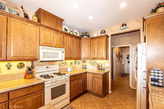 kitchen featuring light stone countertops, light tile patterned floors, and white appliances