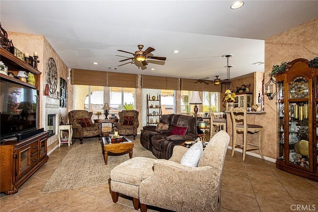 tiled living room featuring ceiling fan, a fireplace, and a wealth of natural light