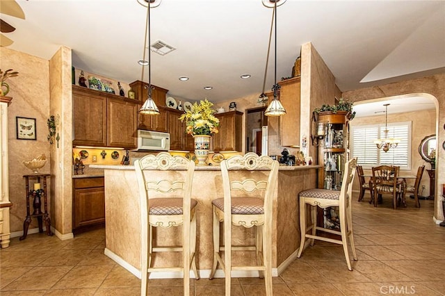 kitchen featuring kitchen peninsula, pendant lighting, and light tile patterned floors