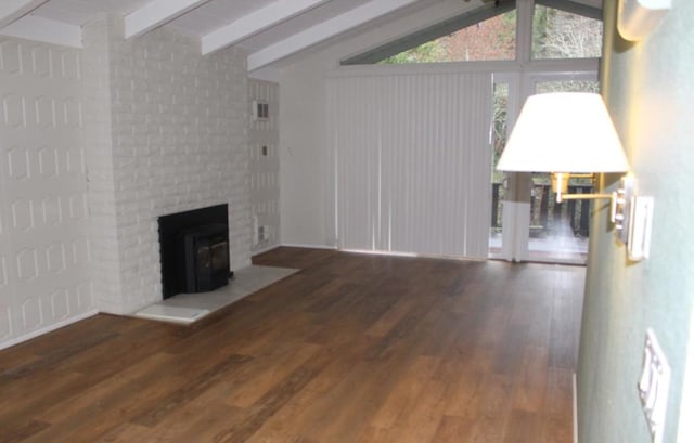 unfurnished living room with a wood stove, wood-type flooring, and lofted ceiling with beams