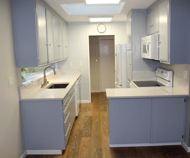 kitchen with white appliances, white cabinetry, sink, dark hardwood / wood-style floors, and kitchen peninsula