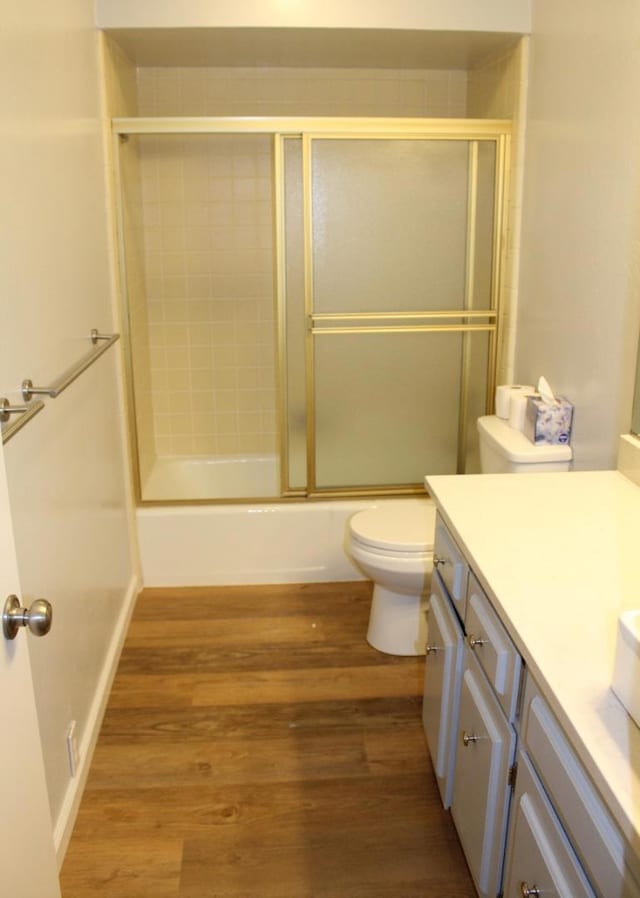 full bathroom with toilet, enclosed tub / shower combo, wood-type flooring, and vanity