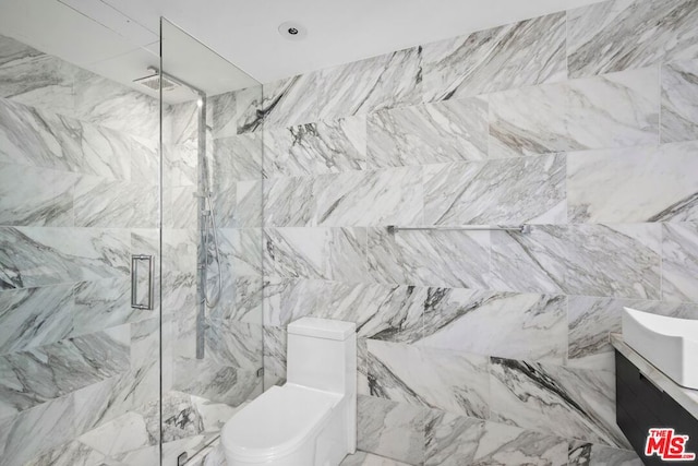 bathroom with vanity, toilet, a shower with shower door, and tile walls