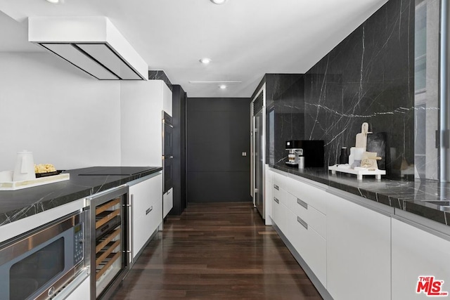 kitchen with stainless steel microwave, white cabinets, tasteful backsplash, dark hardwood / wood-style flooring, and beverage cooler