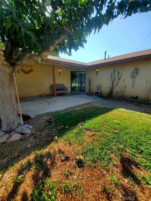 back of property featuring a yard and a patio