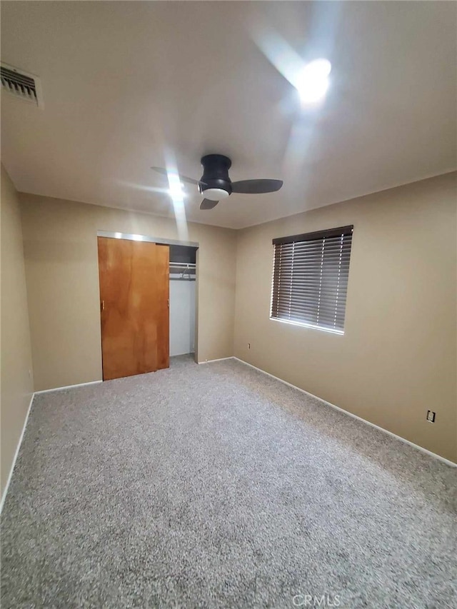 unfurnished bedroom with carpet flooring, ceiling fan, and a closet