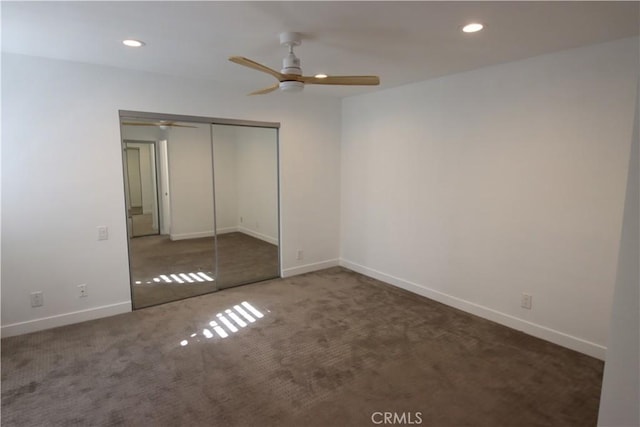 unfurnished bedroom with ceiling fan, a closet, and dark colored carpet