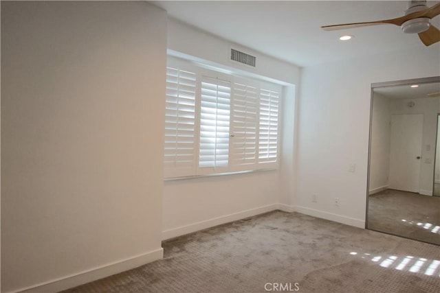 empty room featuring ceiling fan and light colored carpet