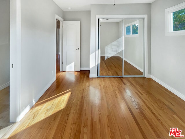 unfurnished bedroom with light hardwood / wood-style flooring and a closet