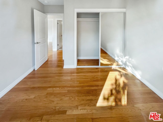 unfurnished bedroom featuring a closet and hardwood / wood-style flooring